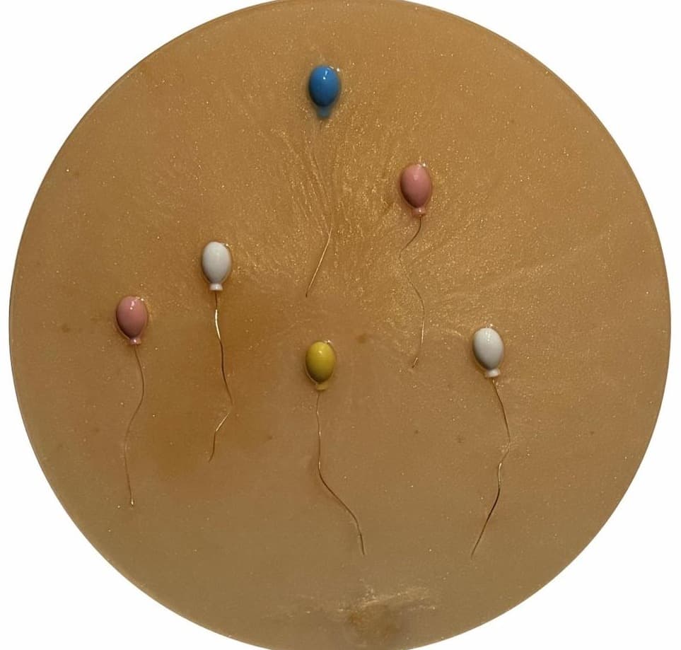 Round golden panel with pastel balloons in pink, white, yellow and blue
