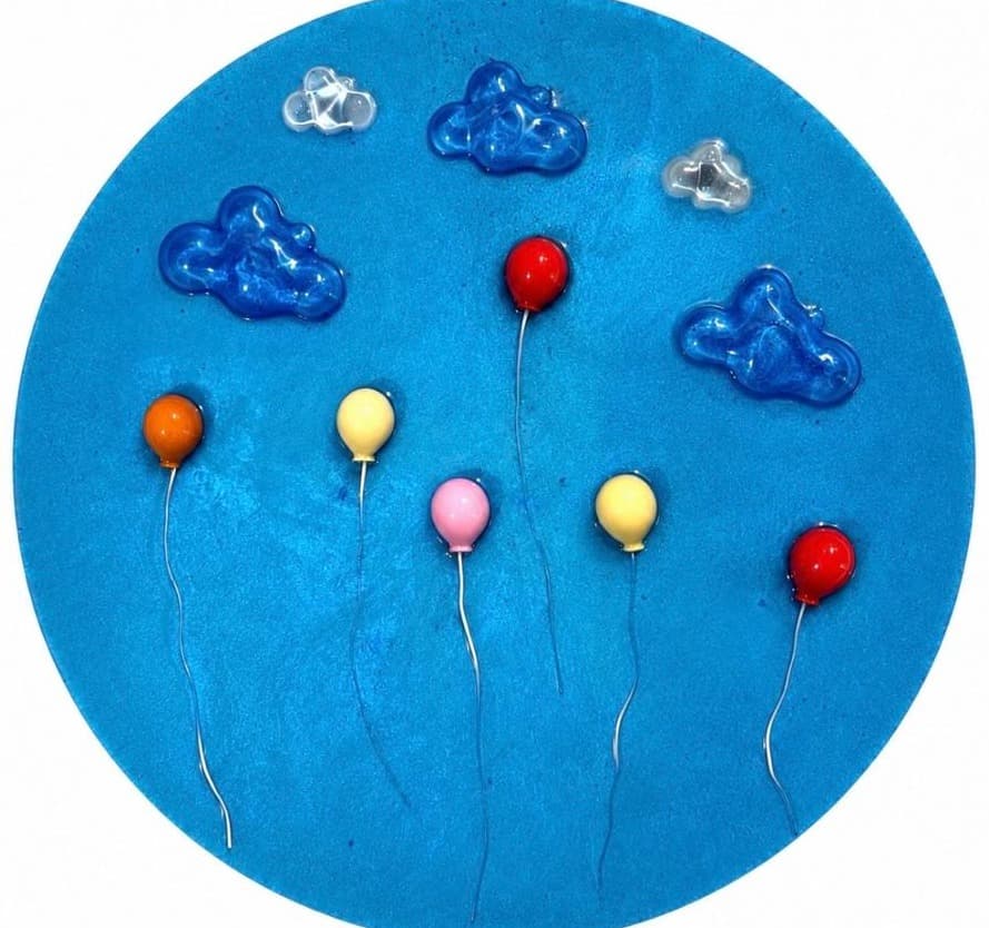 Round bright blue panel with blue glass clouds and red, orange, yellow and pink balloons