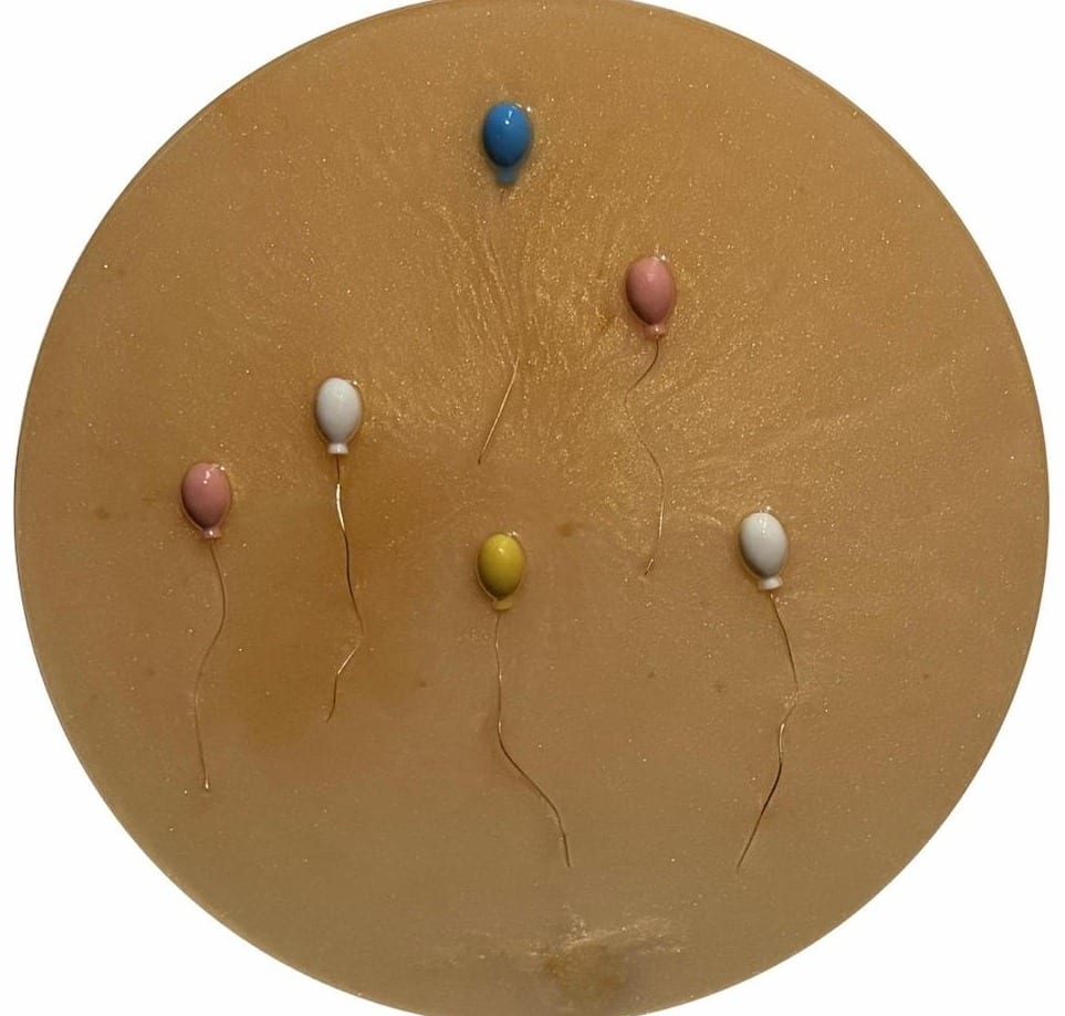 Round golden panel with pastel balloons in pink, white, yellow and blue