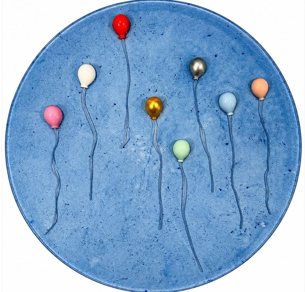 Round blue speckled panel with balloons in red, pink, white, gold, silver, mint and peach