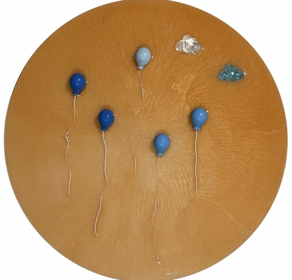 Round ochre panel with sculptural blue balloons and two translucent clouds